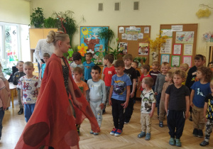 Na tym zdjęciu widać dzieci, które wraz z tancerką wykonują układ baletowy.
