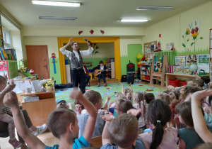 Zdjęcie przedstawia dzieci oraz wokalistę podczas wspólnego biesiadowania.