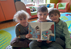 Na tym zdjęciu widać Tymka i Julka z grupy III oraz Filipa z grupy IV prezentujących kolejną ilustrację w czytanej książeczce.
