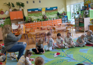 Na tym zdjęciu widać dzieci słuchające bajki czytanej przez panią bibliotekarkę.