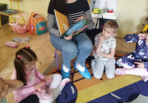 Na tym zdjęciu widać panią bibliotekarkę czytającą dzieciom książkę.