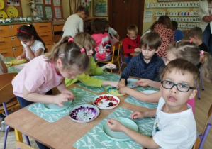 Zdjęcie przedstawia dzieci wykonujące biżuterię dla mamy.