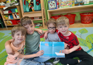 Zdjęcie przedstawia Julka, Tymka, Mieszka i Filipa z grupy III prezentujące jedną z ilustracji w czytanej książeczce.