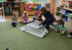 Zdjęcie przedstawia nauczycielkę prowadzącą zajęcie oraz dzieci.