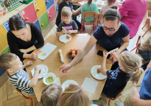 Na tym zdjęciu widać dzieci oraz rodziców ozdabiających babeczki.