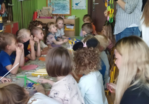 Zdjęcie przedstawia dzieci wraz z rodzicami podczas wykonywania pracy plastycznej.