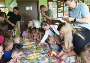 Zdjęcie przedstawia dzieci wraz z rodzicami podczas wykonywania pracy plastycznej.