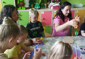 Zdjęcie przedstawia dzieci wraz z rodzicami podczas wykonywania pracy plastycznej.