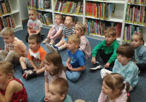 Na tym zdjęciu widać dzieci słuchające bajki czytanej przez panią bibliotekarkę.