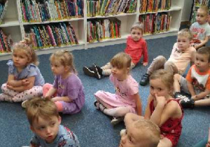 Na tym zdjęciu widać dzieci słuchające bajki czytanej przez panią bibliotekarkę.