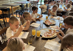 Na tym zdjęciu widać dzieci we włoskiej pizzerii spożywające pizzę.