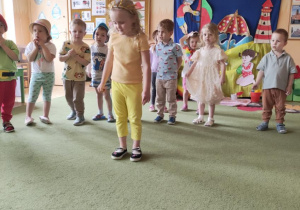Zdjęcie przedstawia Natalkę, która recytuje wierszyk oraz pozostałe dzieci w tle.