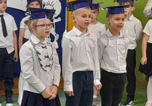 Zdjęcie przedstawia Oliwię, Wiktora i Maksyma recytujących wierszyk.
