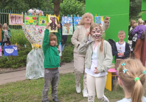 Na tym zdjęciu widać nauczycielkę prowadzącą aukcję prac oraz dzieci.