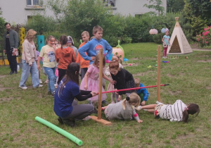 Zdjęcie przedstawia dzieci wraz z prowadzącą podczas jednej z konkurencji sprawnościowych.
