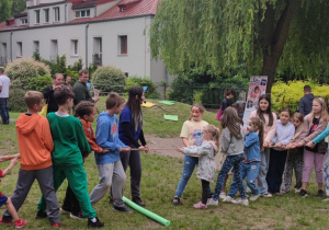 Zdjęcie przedstawia dzieci wraz z prowadzącą podczas kon konkurencji przeciągania liny.