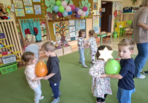 Zdjęcie przedstawia dzieci podczas zabawy muzyczno - ruchowej "Taniec z balonami".