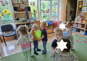 Zdjęcie przedstawia dzieci podczas zabawy muzyczno - ruchowej "Taniec z balonami".