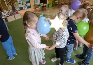 Zdjęcie przedstawia dzieci podczas zabawy muzyczno - ruchowej "Taniec z balonami".