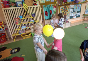Zdjęcie przedstawia dzieci podczas zabawy muzyczno - ruchowej "Taniec z balonami".