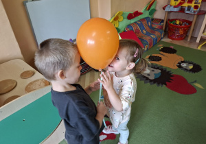 Zdjęcie przedstawia dzieci podczas zabawy muzyczno - ruchowej "Taniec z balonami".