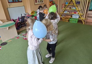 Zdjęcie przedstawia dzieci podczas zabawy muzyczno - ruchowej "Taniec z balonami".