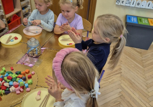 Zdjęcie przedstawia Aurelkę, Jagodę L. i Natalkę M., które lepią lizaki z masy cukrowej.
