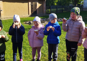 Na tym zdjęciu widać kilkoro dzieci podczas degustacji kromek chleba z masłem wcześniej wyrobionym w maselnicy.