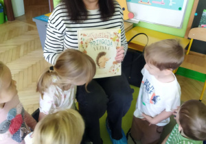 Na tym zdjęciu widać panią bibliotekarkę pokazującą dzieciom książeczkę, którą przyniosła do przedszkola.
