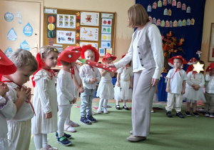 Na tym zdjęciu widać panią dyrektor, która magicznym ołówkiem pasuje dzieci na przedszkolaka w grupie muchomorków.