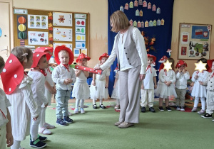 Na tym zdjęciu widać panią dyrektor, która magicznym ołówkiem pasuje dzieci na przedszkolaka w grupie muchomorków.