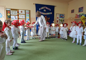 Na tym zdjęciu widać panią dyrektor, która magicznym ołówkiem pasuje dzieci na przedszkolaka w grupie muchomorków.