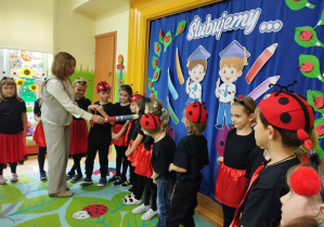 Zdjecie przedstawia dzieci oraz panią dyrektor, która magicznym ołówkiem pasuje je na przedszkolaka w grupie "Biedronek".