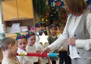 Zdjęcie przedstawia panią dyrektor, która magicznym ołówkiem pasuje dzieci na przedszkolaka w grupie "Jagódek".