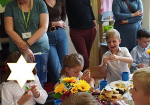 Na tym zdjęciu widać dzieci oraz rodziców podczas poczęstunku.