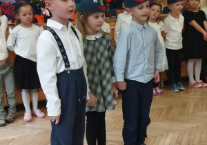 Zdjęcie przedstawia troje dzieci z grupy III recytujących wierszyk.