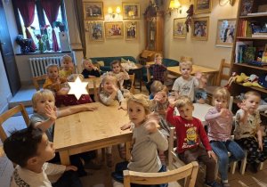 Zdjęcie przedstawia dzieci z grupy "Muchomorków" siedzące przy stolikach w kawiarence.