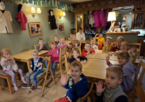 Zdjęcie przedstawia dzieci z grupy "Krasnali" siedzące przy stolikach w kawiarence.