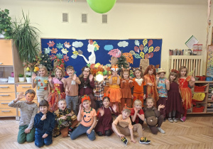Zdjęcie przedstawia dzieci z grupy IV na tle jesiennej dekoracji.