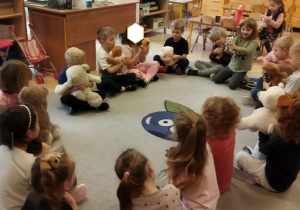 Na tym zdjęcu widać dzieci siedzące w kole podczas zajęcia z wykorzystaniem przyniesionych misiów.