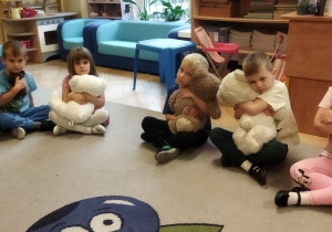 Zdjęcie przedstawia kilkoro dzieci siedzące na dywanie z misiami podczas zajęcia.
