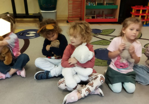 Zdjęcie przedstawia kilkoro dzieci siedzące na dywanie z misiami podczas zajęcia.