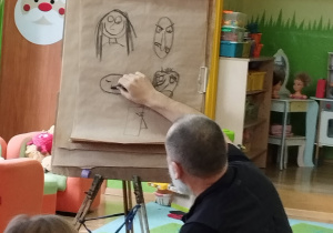 Zdjęcie przedstawia naszego gościa rysującego węglem obrazki.