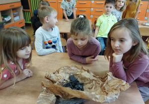 Na pierwszym planie tego zdjęcia widać kilkoro dzieci ogladających węgiel rysunkowy.