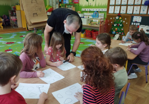 Na tym zdjęciu widać dzieci, które próbują swoich sił w przekształcaniu wzorów graficznych pod okiem pana ilustratora.