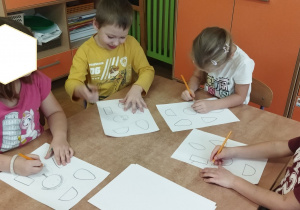 Zdjęcie przedstawia dwie dziewczynki i dwóch chłopców tworzących szkice, przekształcając podane wzory.