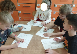 Zdjęcie przedstawia jedną dziewczynkę i czterech chłopców tworzących szkice, przekształcając podane wzory.