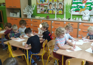 Zdjęcie przedstawia dzieci rysujące szkice, przekształcając wzory na kartkach.