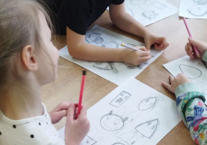Zdjęcie przedstawia kilkoro dzieci szkicujących obrazki.