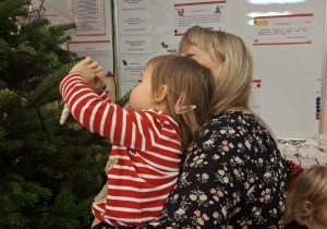 Na tym zdjęciu widać Anielkę wieszającą bombkę na choince.